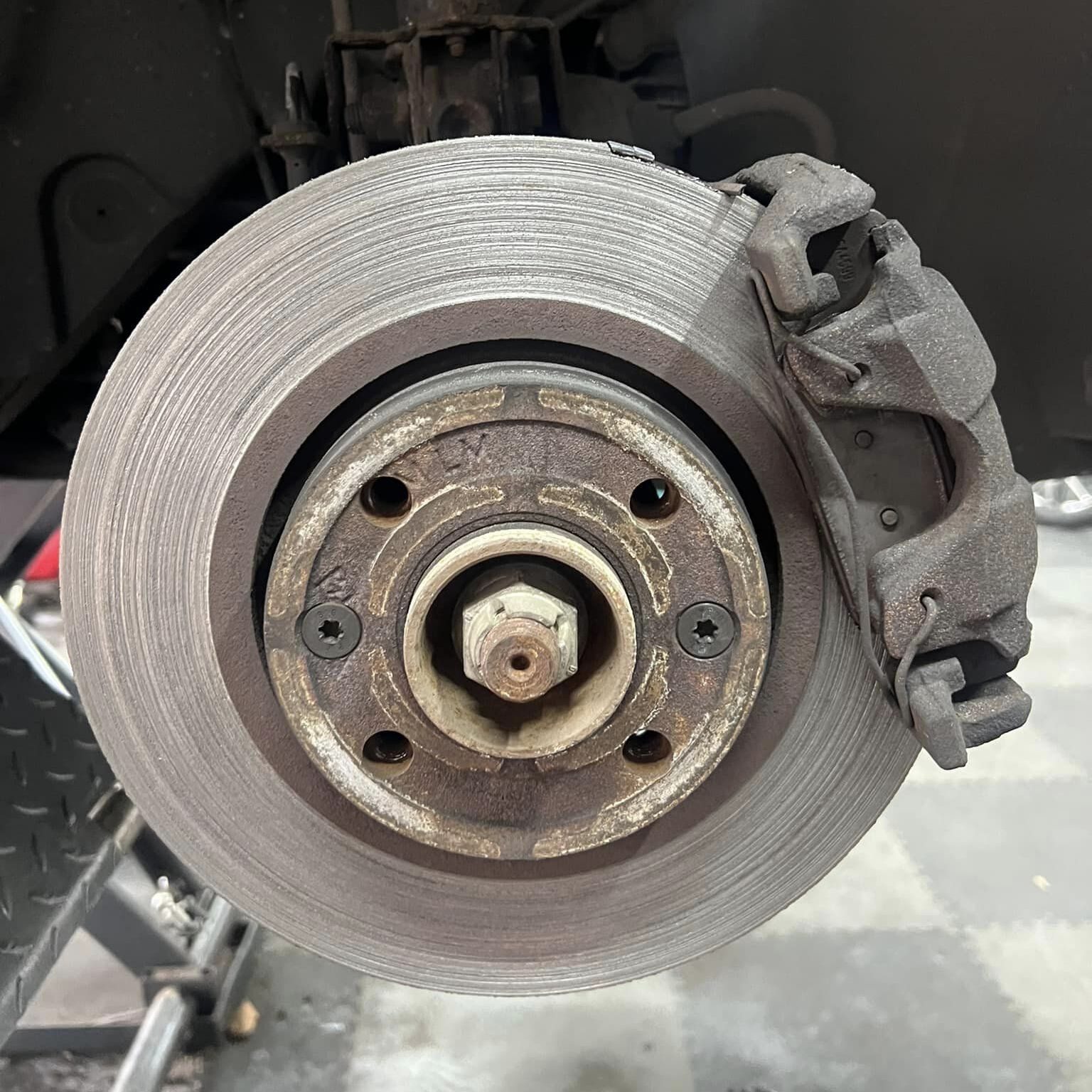 A worn brake disc and caliper before replacement